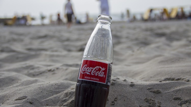 Una botella de Coca Cola en la arena de una playa