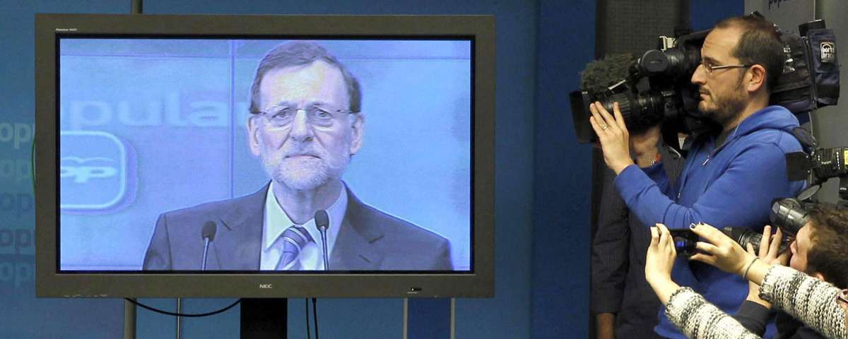 Mariano Rajoy en un televisor y varios periodistas