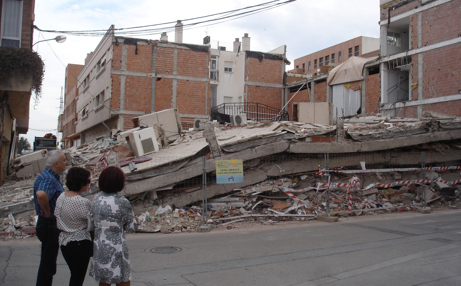 Unas personas viendo un edificio destruido después del terremoto de Lorca