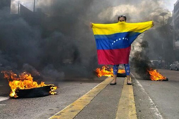 Una persona con la bandera de Venezuela en una manifestación
