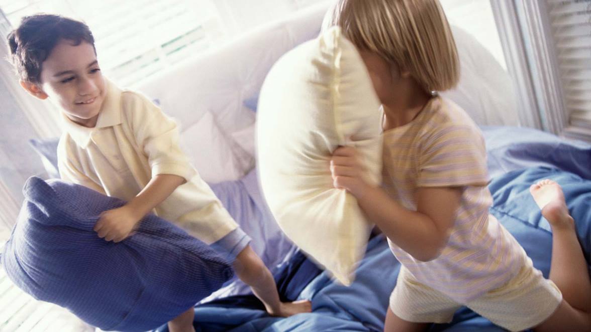 Dos niños jugando con almohadas