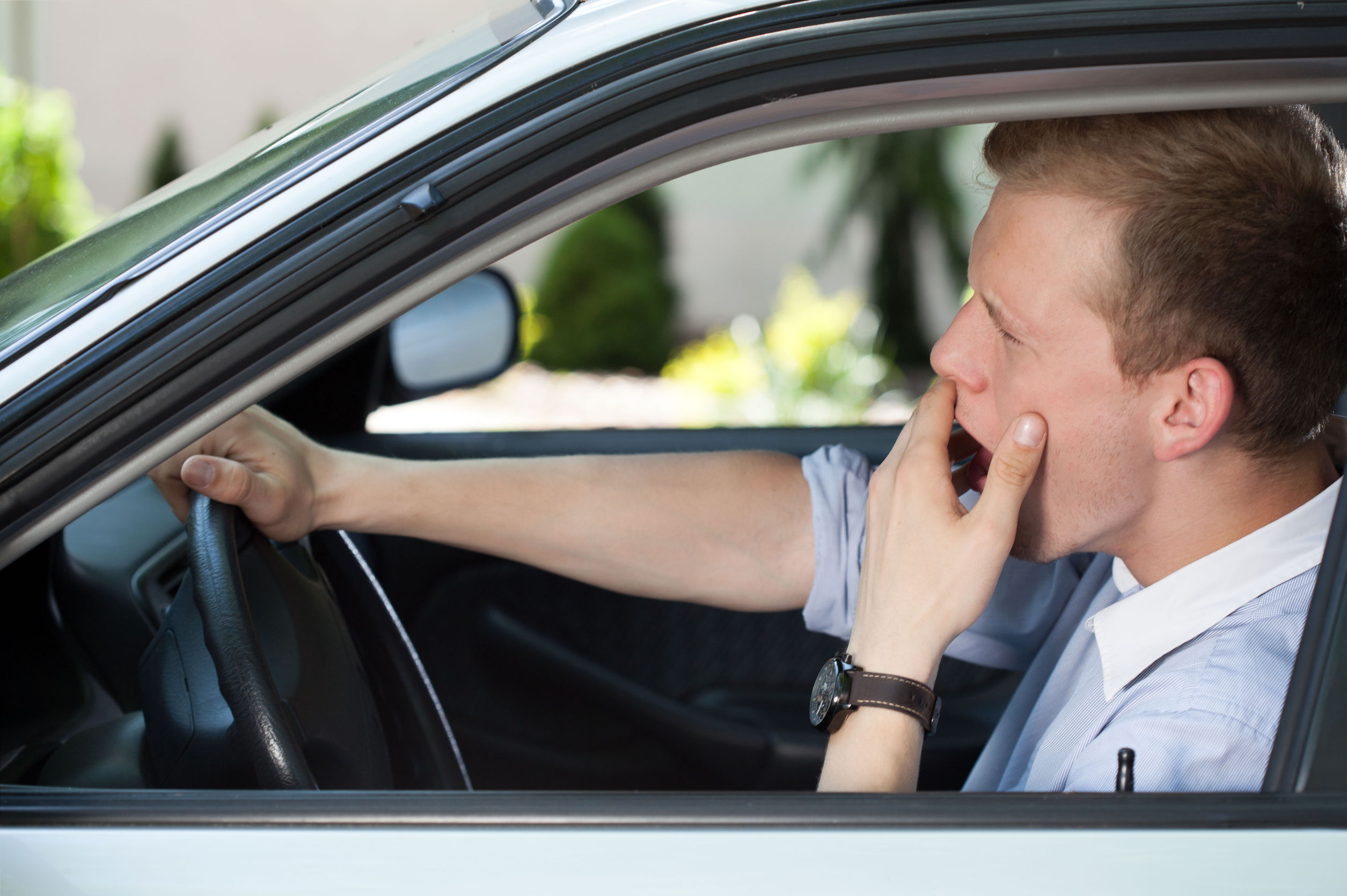 Un hombre bostezando en un coche