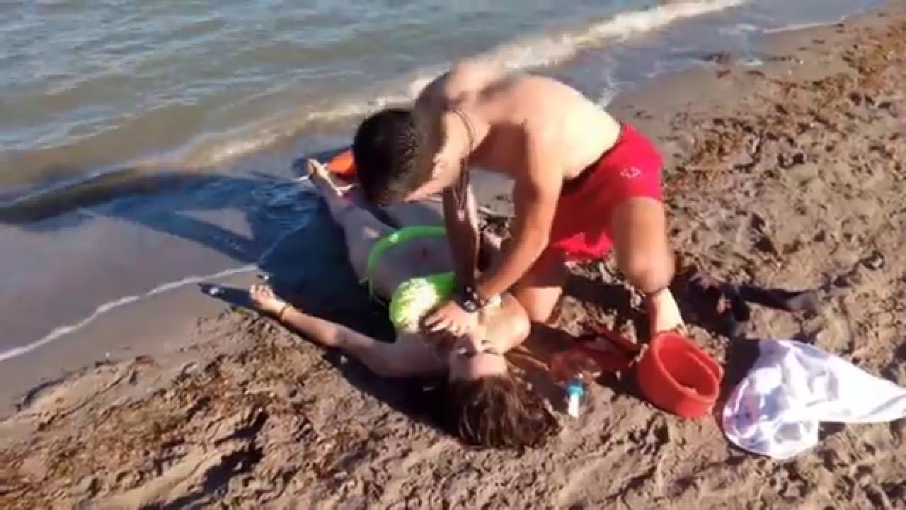 Un socorrista auxiliando a una mujer en la playa