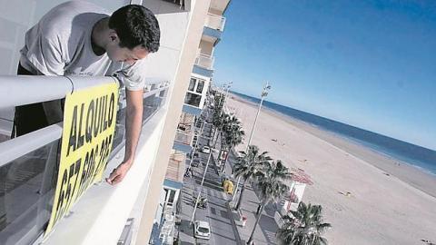 Un hombre poniendo un letrero de "Se Alquila" en una vivienda