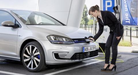 Una mujer cargando un coche eléctrico