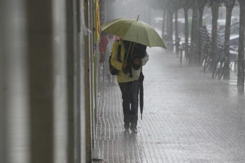 Una mujer con un paraguas caminando por la calle