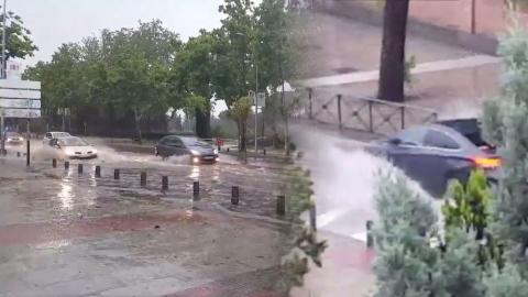 Coches pasando por un gran charco durante una tormenta