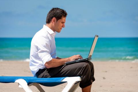 Un hombre en una playa trabando con su ordenador