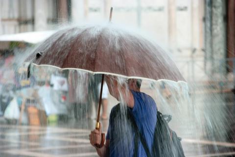 Una mujer con un paraguas caminando por la calle