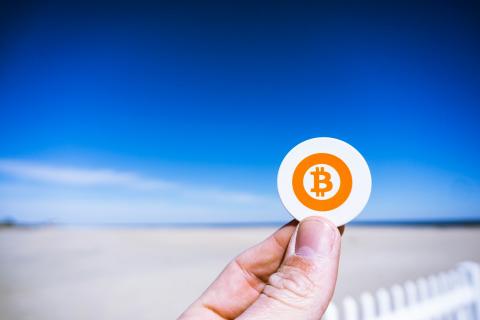 Mano sujeta Bitcoin en playa 